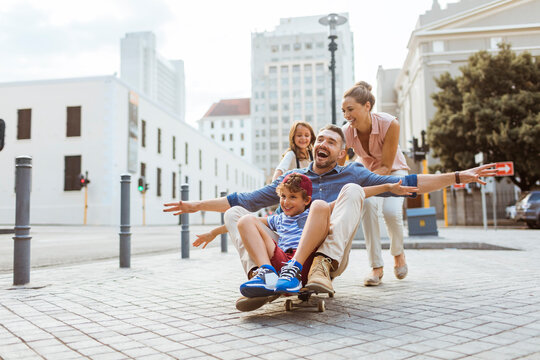 Happy family riding a skateboard on a city street