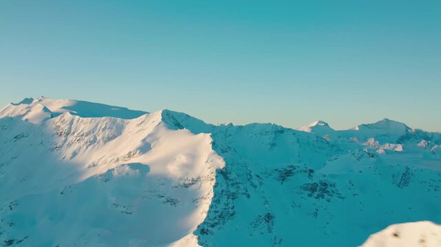 Aerial view of snow-covered mountains under clear blue sky