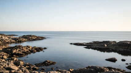 Serene rocky coastline with calm waters under clear blue sky