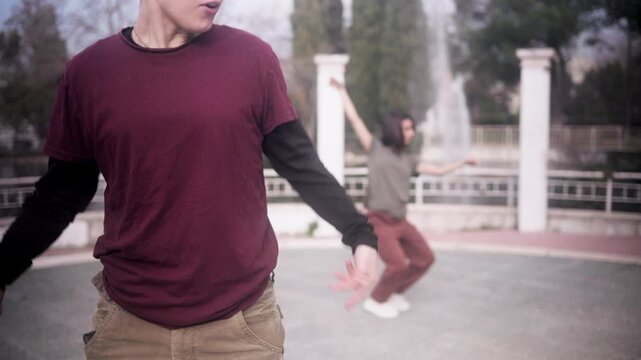 Young beatboxer freestyling while woman dances hip hop in a park