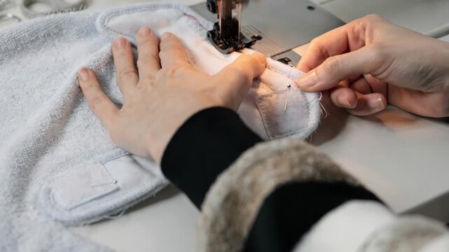 Medium shot of a baby bib being shaped and stitched with hookandloop fasteners highlighting precise sewing techniques and absorbent fabric details.