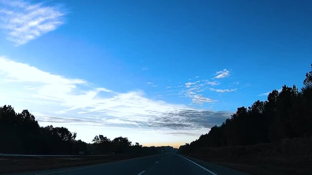 POV driving in the evening clouds, blue sky split highway