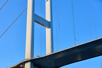 Obraz premium Suspension bridge against clear blue sky with steel cables and tall pillars