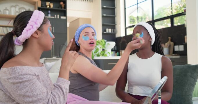 African American friends learning applicator use from center woman for under-eye patches on couch