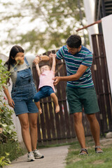 Happy parents lifting their child while playing outdoors near their home