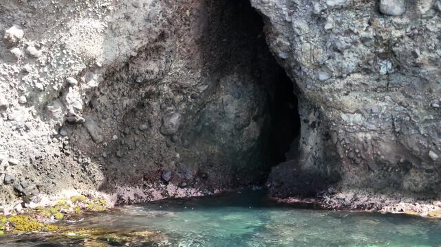 Grotte aux Chauves-Souris in Les Anses-d'Arlet: dark sea cave mouth set in volcanic cliffs opening onto clear turquoise Caribbean water, a secluded coastal grotto for exploration in Martinique island