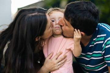 Fototapeta premium Parents Showing Affection to Their Child Outdoors in a Loving Family Moment