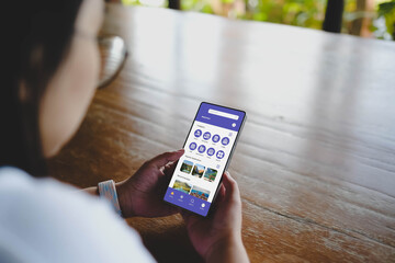 A person using a travel booking mobile application on a smartphone to plan a vacation and search...