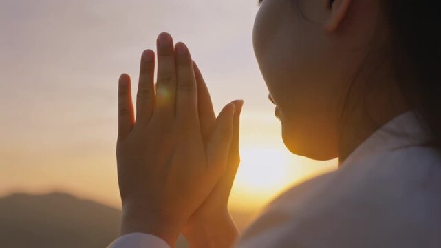 Silhouette hands of prayer woman worship God in the morning with sunrise sky background.