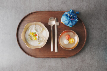 한국 설날 명절 떡국, 놋그릇에 담긴 설 떡국과 송편 방울떡, 복주머니, 우드 트레이