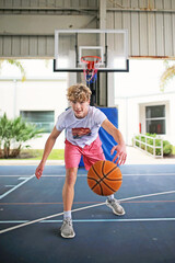 Teen Boy Playing Basketball Outside on Outdoor Court