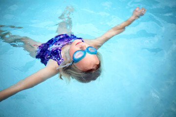 Child Relaxing and Floating in Swimming Pool Water on Her Back