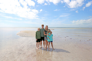 Happy Mother and Her Children On A Beautiful Beach on the Ocean