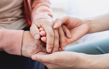 A woman holds hands and gives love to her elderly mother at home, creating bonding and happiness. love and care concept