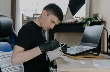 One person peels off letter stickers on a laptop keyboard with tweezers.