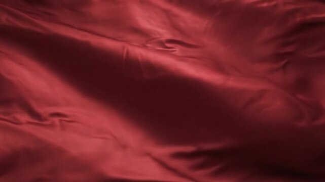 Flowing, lustrous red fabric with dynamic folds and shadows, creating a smooth, rich visual