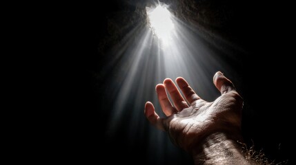 A hand reaching out towards a light source in a dark cave.
