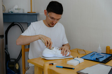 A young man repairs shoes at home.