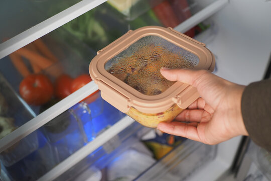 Hand reaches for container in refrigerator with vegetables
