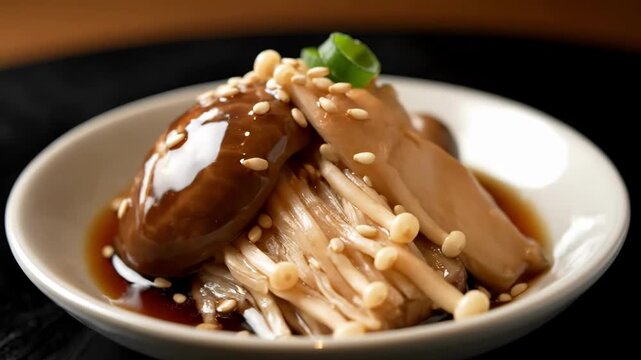 Elegant close-up of glazed enoki mushrooms and a large shiitake cap topped with sesame seeds and savory soy sauce glaze, served as a gourmet Japanese appetizer on a white plate.