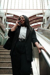 Businesswoman talking on phone while ascending escalator in station