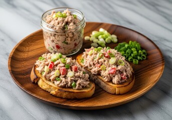 Delicious tuna salad on toasted bread with vegetables on a wooden plate