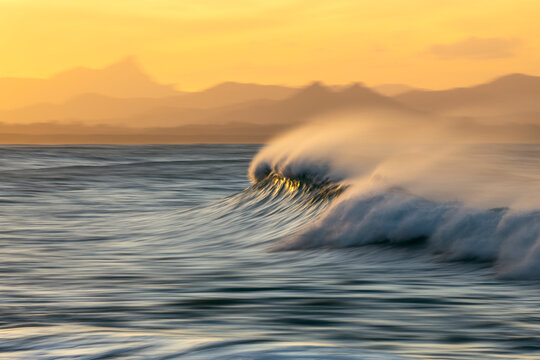 Slow shutter speed photograph of a breaking ocean wave at Byron Bay, Australia, captured at sunset.