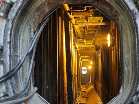 View inside a confined space industrial chamber with lighting and piping, highlighting restricted access area, safety procedures, inspection work, and hazardous environment in heavy industry.
