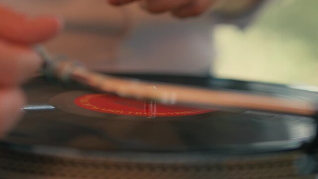 The DJ puts the vinyl record on the record player to play