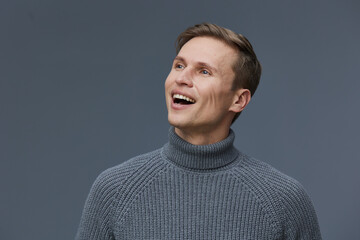 Obraz premium Smiling man wearing gray knitted turtleneck sweater looking away isolated on dark gray background, happy cheerful male portrait, digital nomad, freelance communication concept
