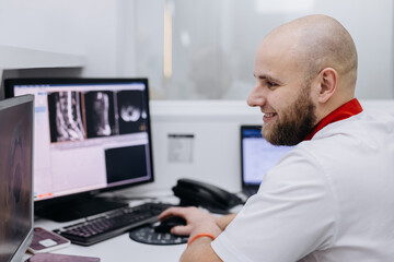 Fototapeta premium Doctor analyzing MRI scans on computer screen in modern clinic. Diagnostic and healthcare concept.
