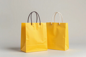 Two bright yellow paper shopping bags with black handles on grey background