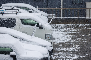 雪の日に凍結防止でワイパーを立てて駐車された車列