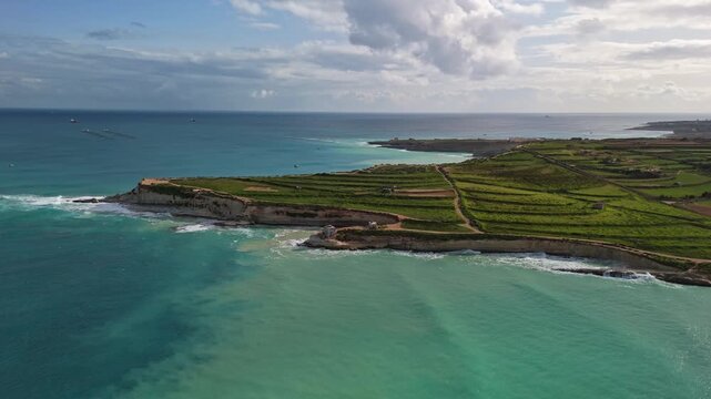 Gorgeous aerial view of the Munxar Path in winter greenery, with the colorful, moody, wavy Mediterranean Sea around, on a stormy day near Marsaskala, Malta.
