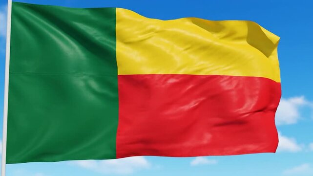 The vibrant national flag of Benin proudly waves against a clear blue sky