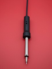Obraz premium Close-Up Shot Of A Soldering Iron Tip Against Vibrant Red Backdrop Ideal For Electronics Repair Tutorials Or Product Displays