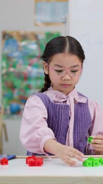 Young Asian Girl Using Green Math Blocks in a Classroom Setting