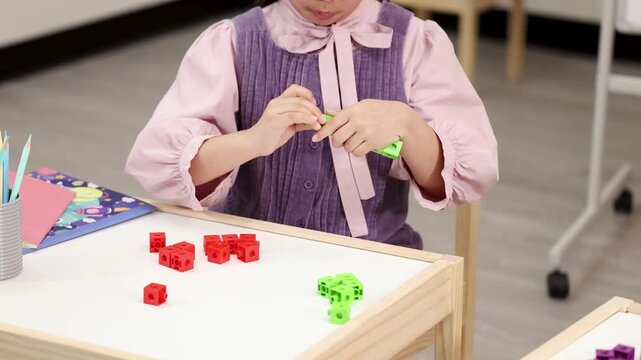 Young Child Sorting and Connecting Colorful Math Manipulative Blocks in Classroom