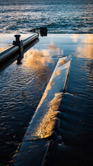 Fototapeta premium A submarine surfacing in the ocean near a pier at sunset.