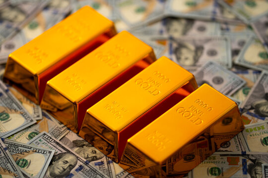Gold bars and money. Golden bars stacked with US dollars in background. Gold bars for secure capital growth. Dollars money and gold concept. Financial success and saving Gold.