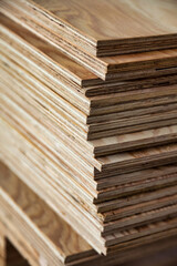 Naklejka premium A collection of plywood sheets is organized in a workshop, showcasing the layered structure of the material. This setting highlights the essential role of plywood in manufacturing and construction.