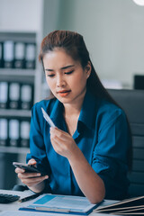 Young businesswoman is holding two credit cards with a worried expression, trying to decide which...