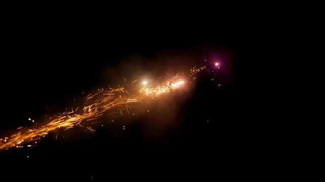 A firework streaks across background, leaving a brilliant golden trail of streaming sparks and a soft orange glow. 
