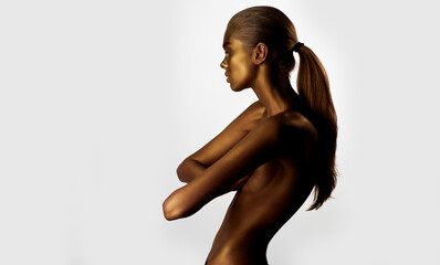 Gold nude body paint. Sexy naked model in gold paint pose on studio isolated background. Beauty with gold body paint. Luxury gold skin art.