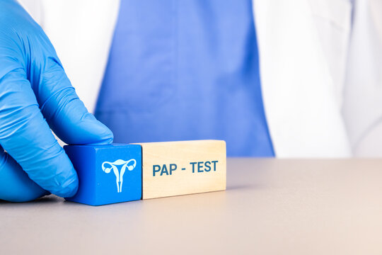 Concept of education on gynecological check-ups, awareness of the Pap smear test, and professional uterine care. The gynecologist's hand arranges wooden cubes with a uterus icon.