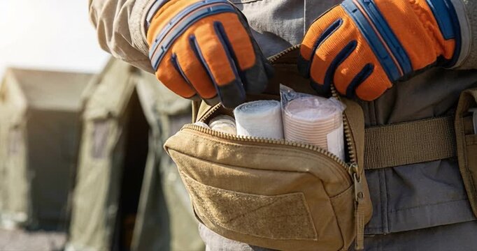 Person preparing medical supplies outdoors with safety gloves