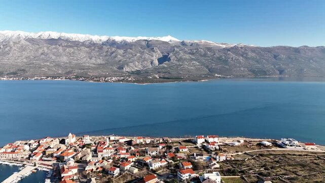 Drone continues orbit around Vinjerac revealing coastline, small beaches, coves and hills with road cutting through the landscape on a sunny winter day, Dalmatia, Croatia.