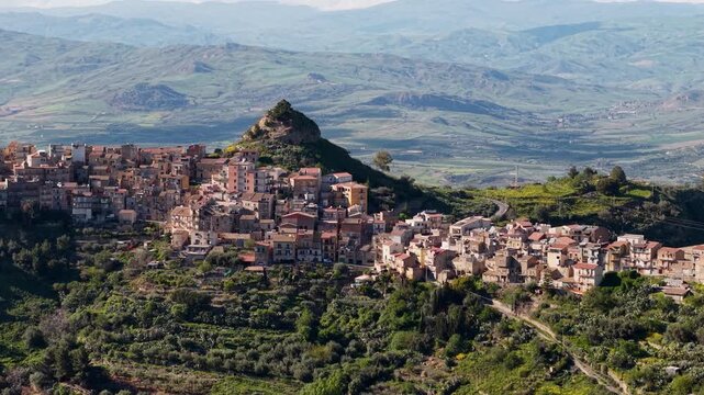 Aerial view over lush Centuripe Italian hill town and picturesque Castello di Corradino peak