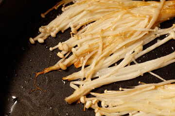 Enoki mushrooms are fried in a pan