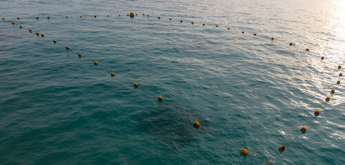A large body of water with yellow buoys in the water © schankz
